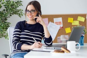 Portrait of confident young woman working in her office with mobile phone.